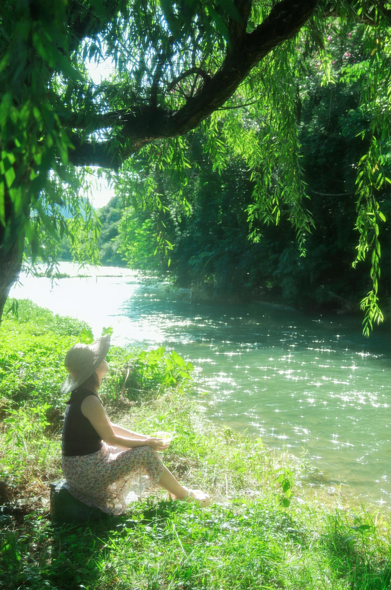 河边的场景选得妙，河水的绿、柳枝的翠，还有人物身上的穿搭，黑背心、花裙子、大草帽