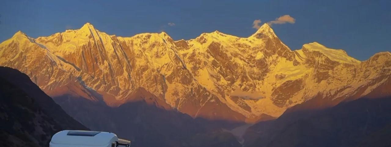 阳光倾洒而下，雪山宛如被施了魔法，瞬间变成一座金山，闪耀着令人迷醉的金色光辉。