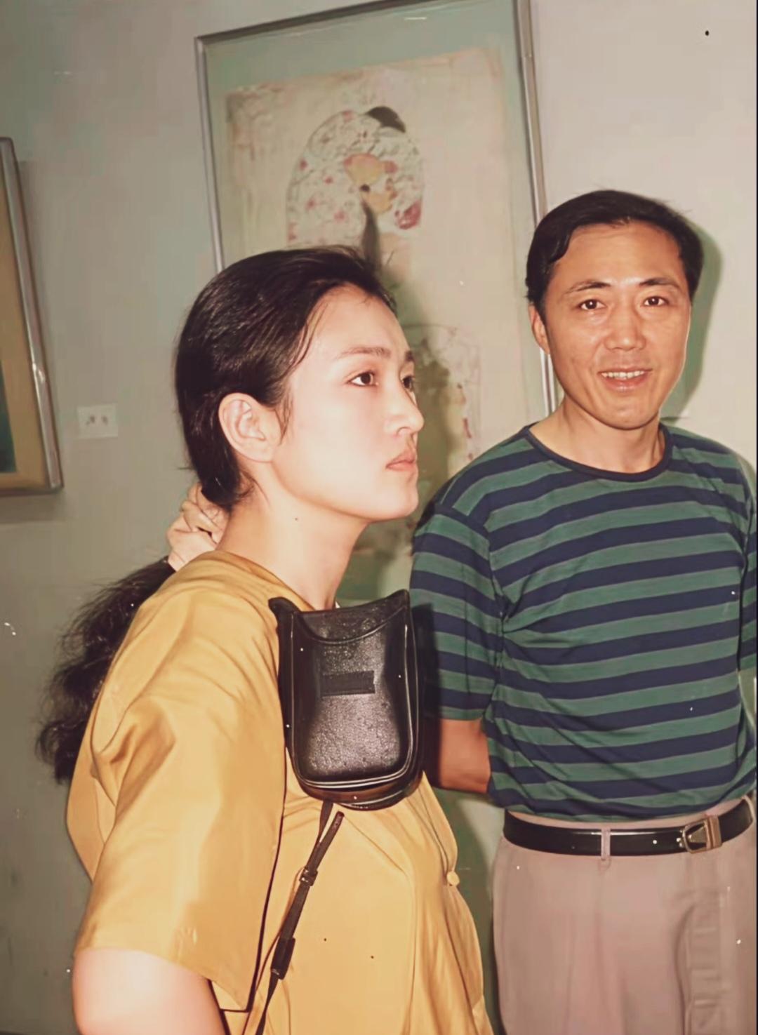 年轻时候的巩俐身着淡黄色短袖，斜挎老式相机皮包，侧头望向画作，气质沉稳，侧脸线条