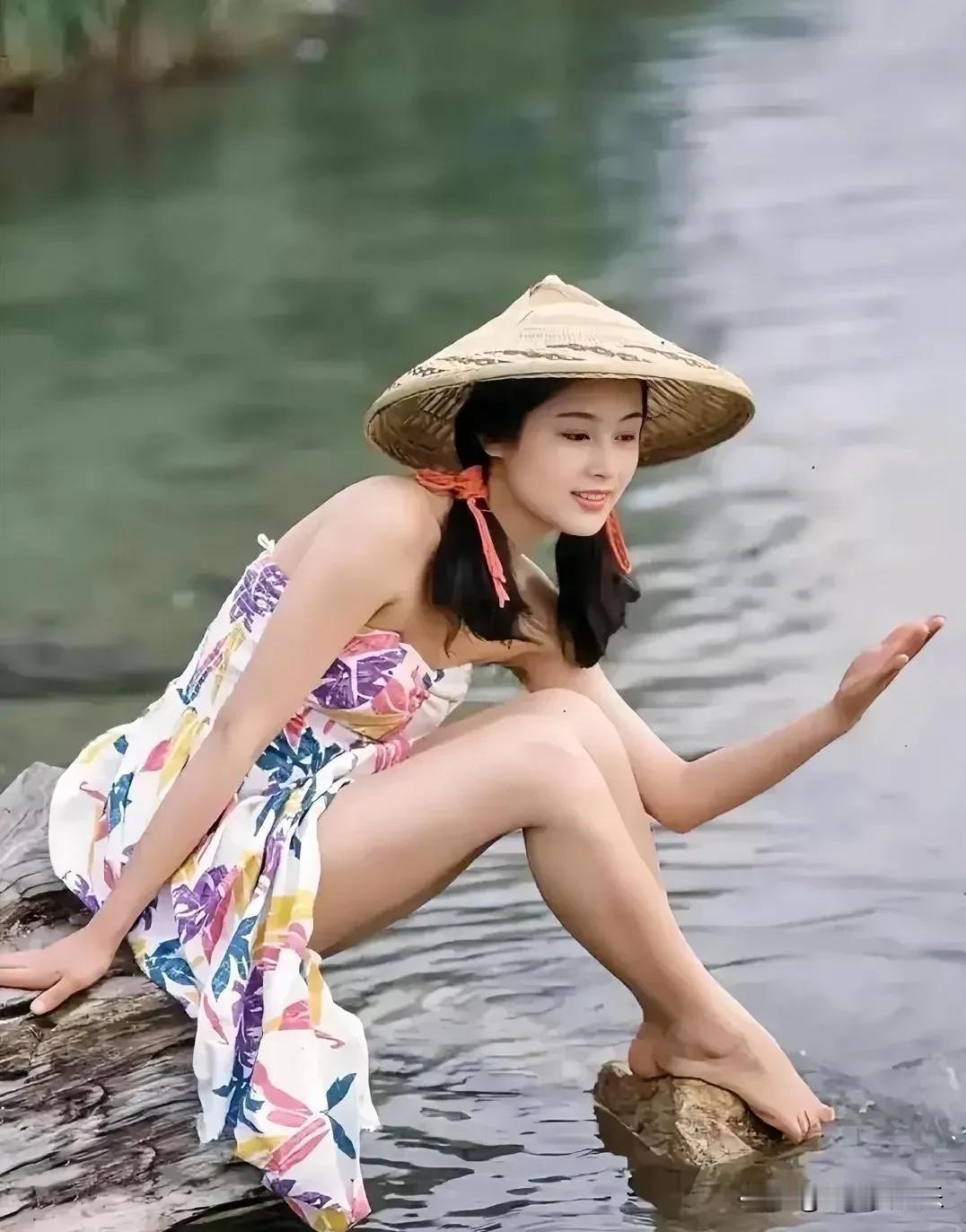 哇，像仙女下凡悠然地坐在河边石头上，头戴斗篷草帽，淡色的花裙，清秀的容貌，越来越