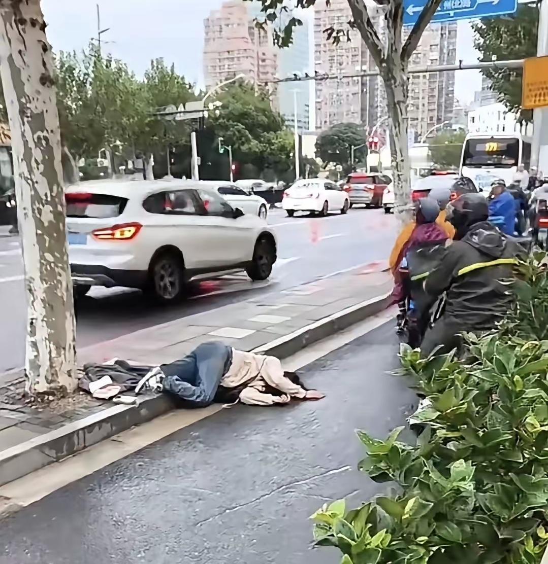 你能想象吗？车水马龙的街道上，一女子半个身子横在马路牙子与车道间，处境极其危险！