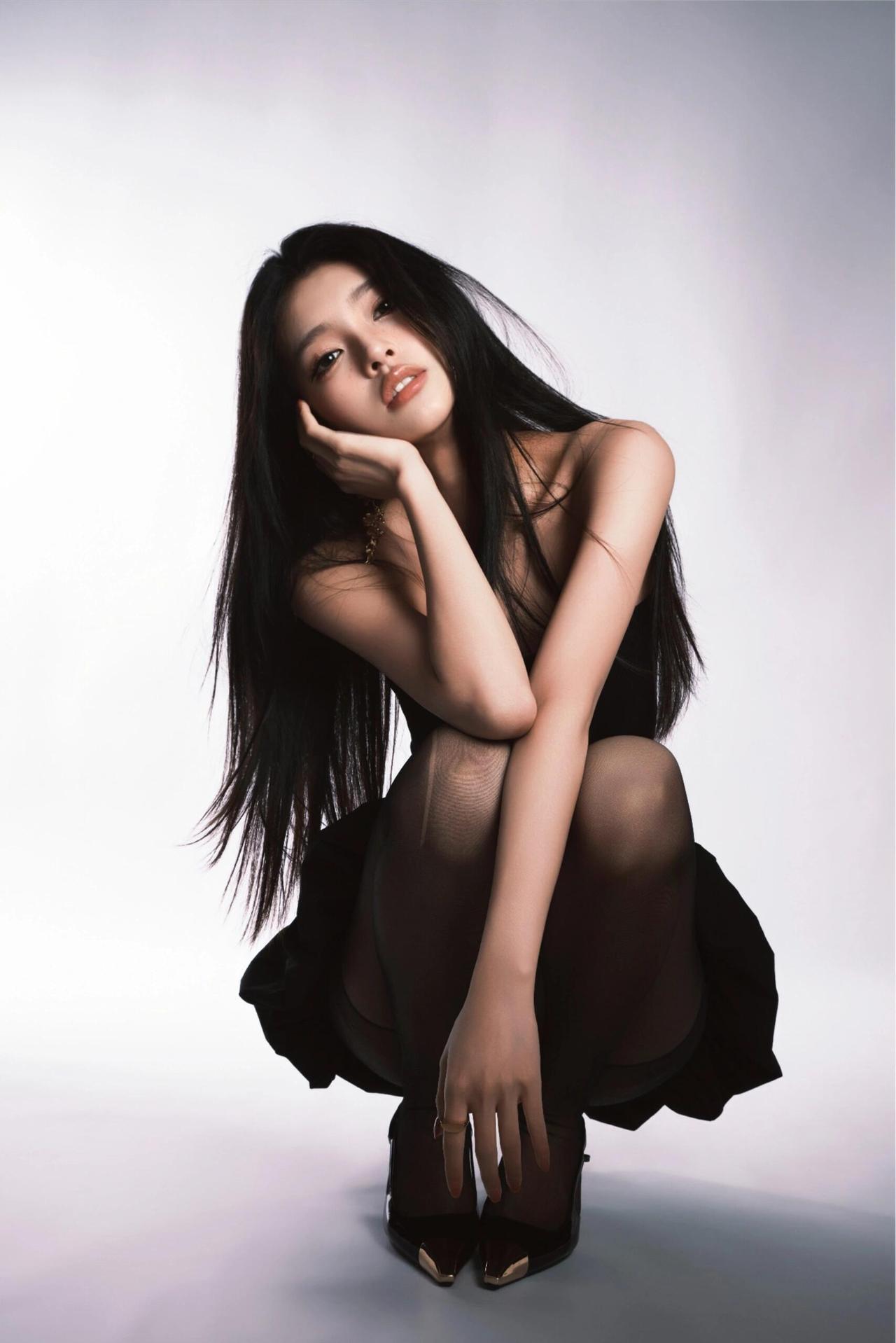 蹲姿是这组照片中最具张力的姿态，人物双膝并拢、身体微微前倾，手肘轻托脸颊，另一只