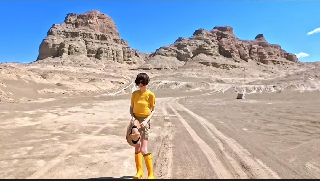 鲁豫在新疆，穿着黄色针织上衣，里面还配了一个白色背心，短裤，黄色高筒靴，瘦高的个