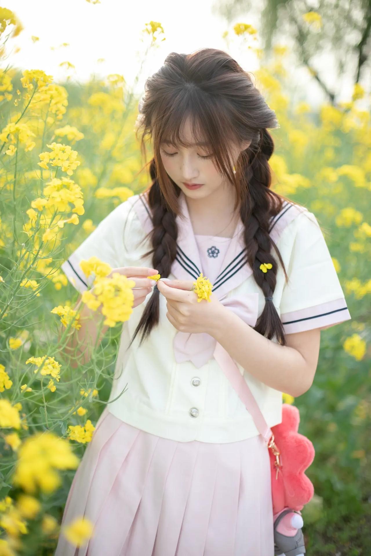 油菜花田里的JK少女！粉色水手服配双麻花辫，手里捏着小黄花，笑起来甜度超标，这画