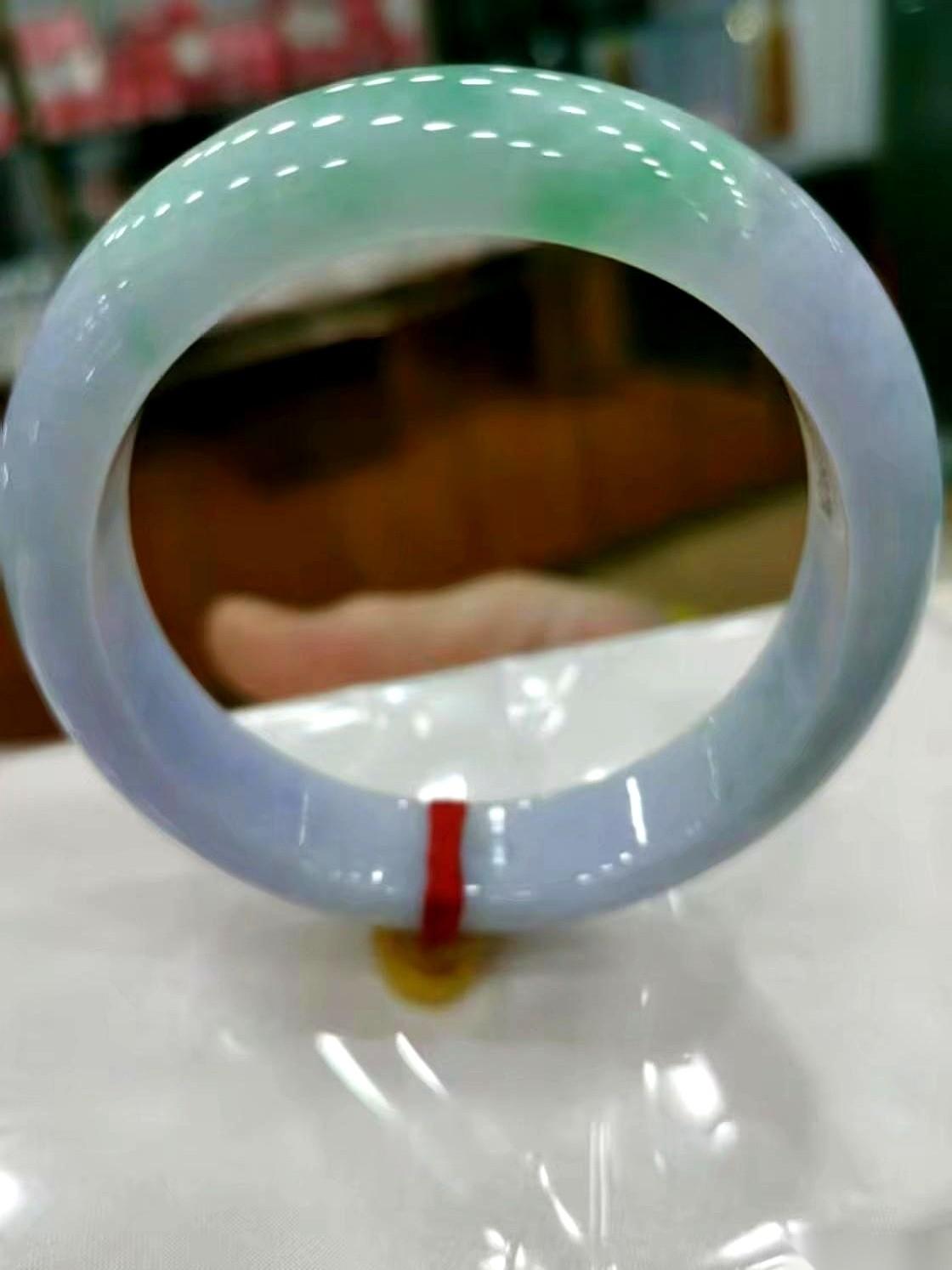 朋友甩来一张照片，一块飘着绿和紫的镯子。
灯光下，水头看着真不错。他劈头盖脸就一