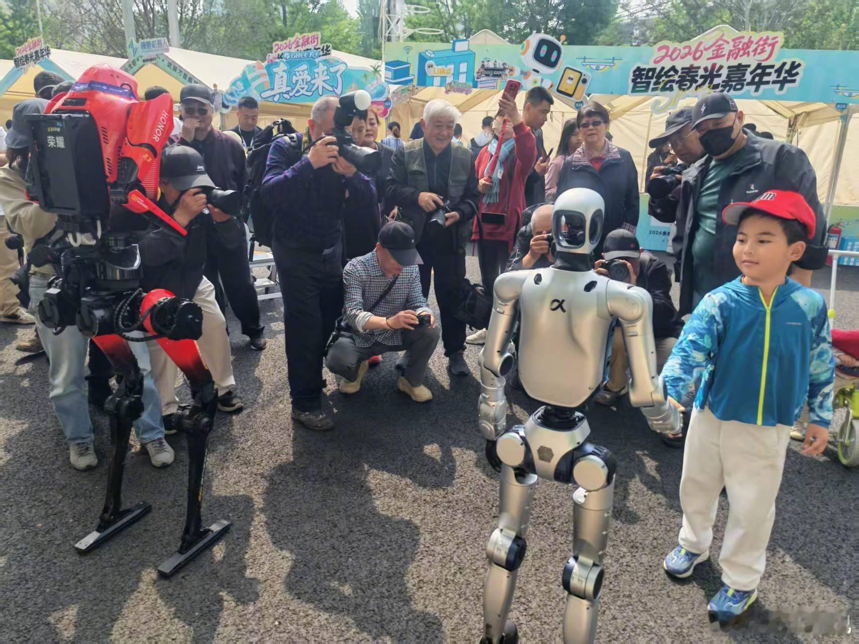 荣耀机器人夺冠后首次亮相 荣耀的机器人们今天在北京金融街陪大朋友、小朋友们一起互
