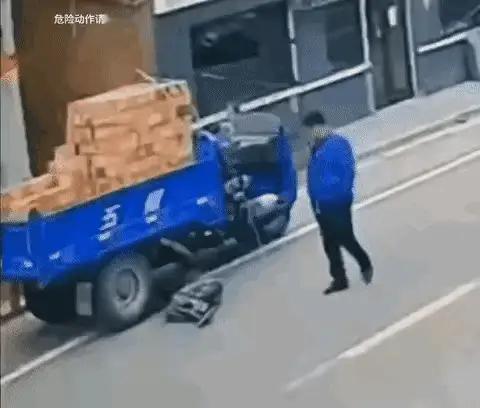 细思极恐。一辆装满砖的三轮车，不知何故，车主躺在车下。这时一位身穿蓝色上衣的年轻