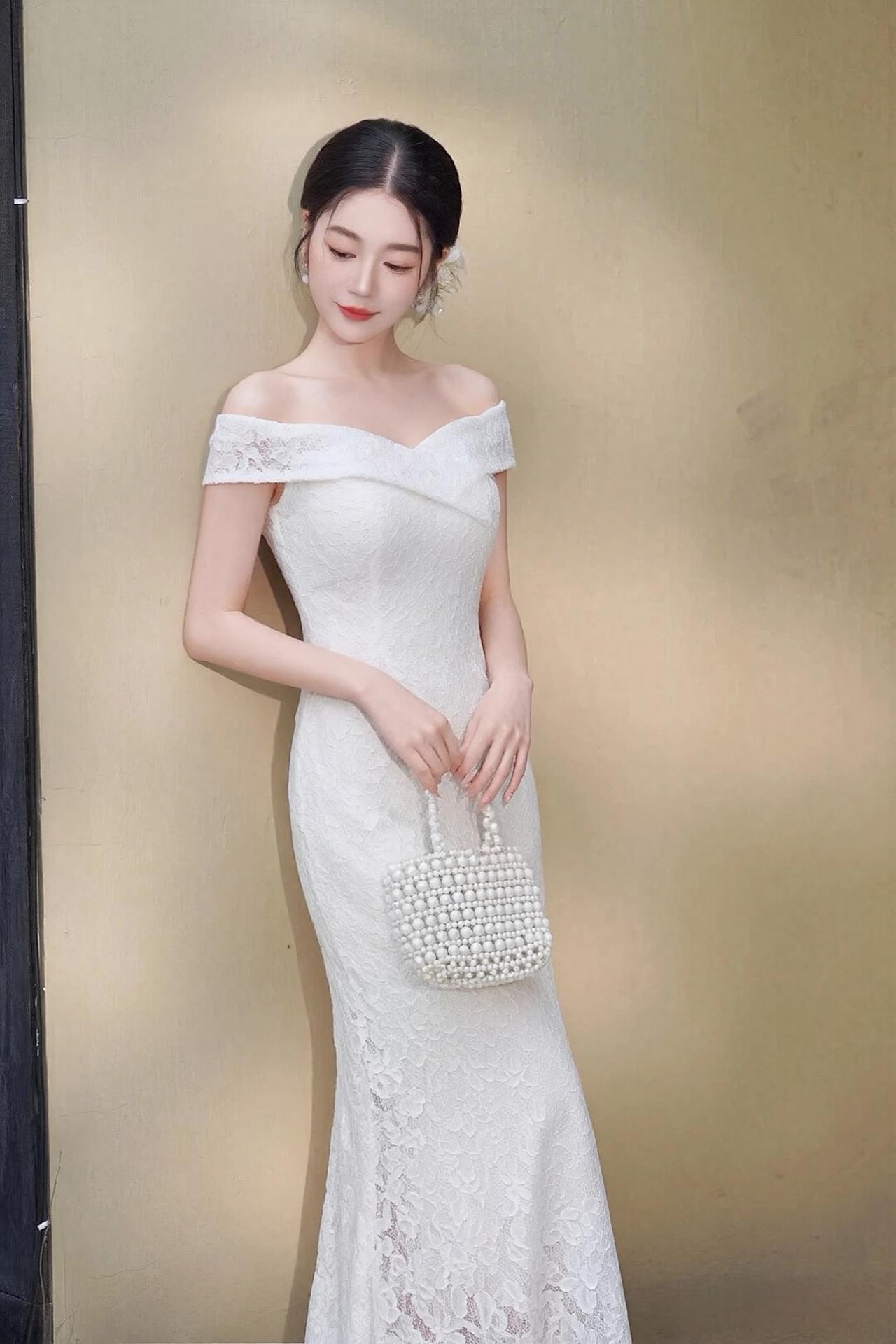 她身姿窈窕，肌肤胜雪，精致的一字肩设计勾勒出优美的锁骨线条，尽显温婉大气。通体的