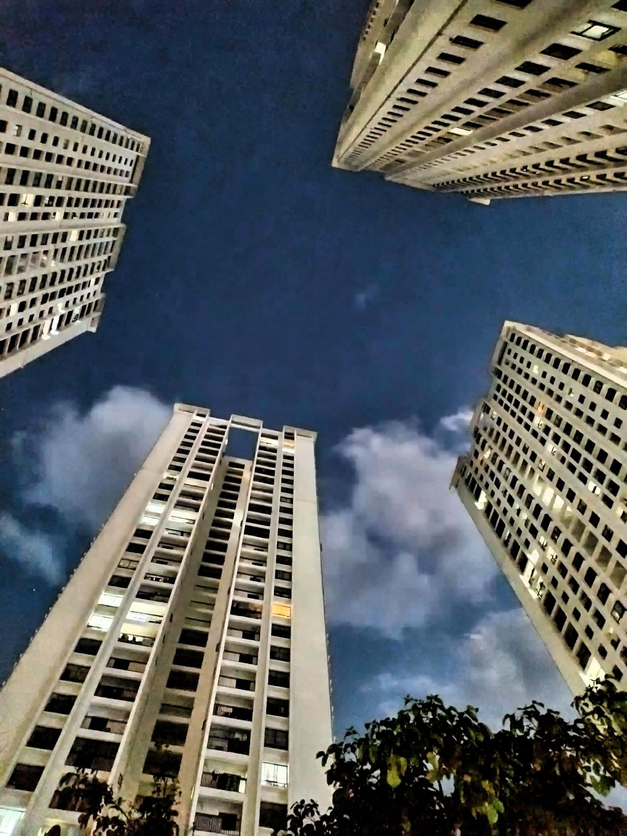 晒图笔记大赛 夜幕下的高楼大厦，云层间透出微光，城市静谧而神秘。高楼林立，直冲云