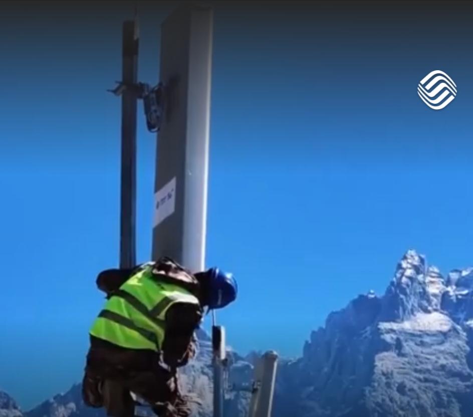 在青山环抱的村落里，一汪碧水映着蓝天，崭新的5G基站铁塔矗立在金黄的田野旁，信号