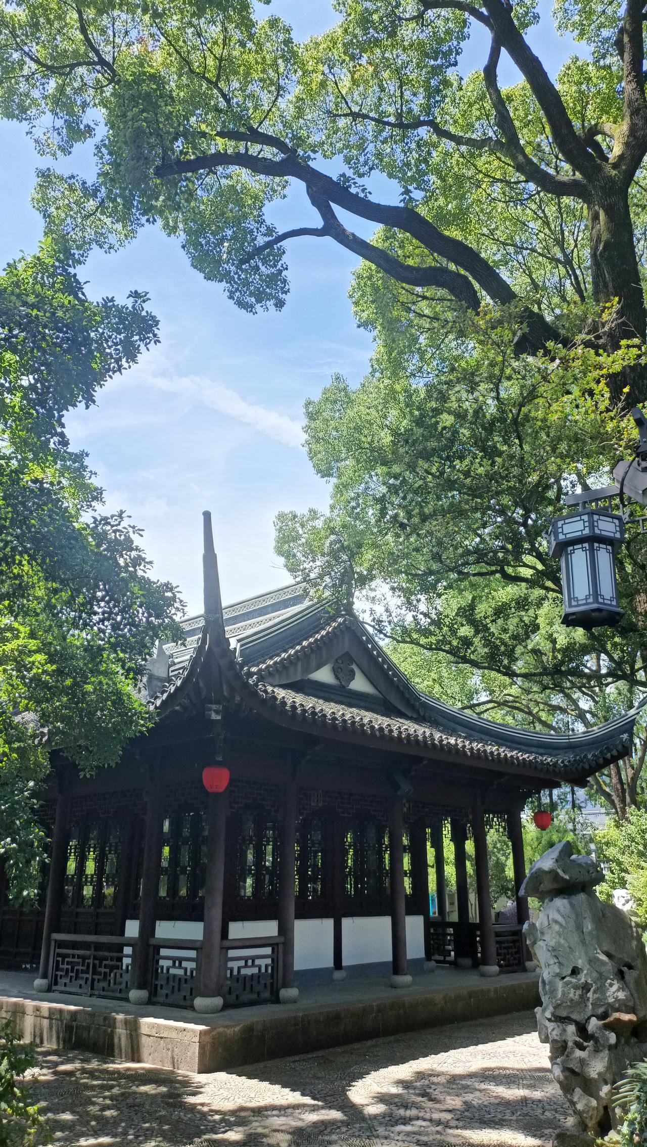 古风庭院，绿树成荫，红灯笼点缀，静谧悠然。
上联：绿树掩映古亭中，
下联：灯笼映