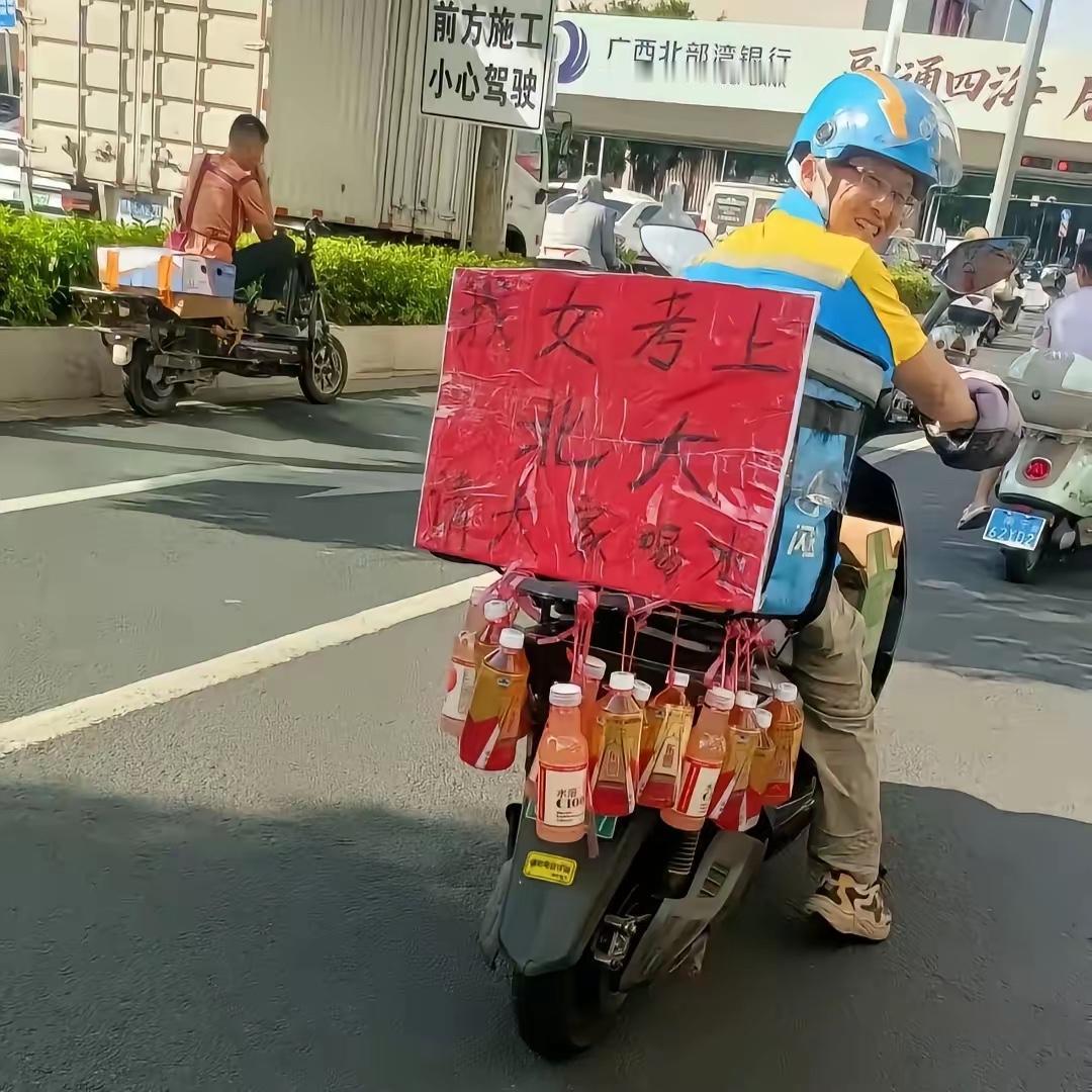 一外卖员在他的外卖箱上贴了一张写着“我女儿考上北大，请大家喝水”的红纸。箱子下面