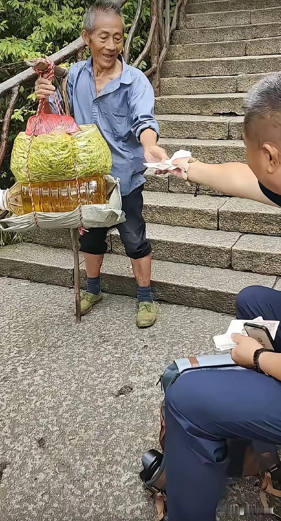 泰山十八盘的石阶上，一位歇脚的江苏游客，对着迎面走来的挑山工做了个动作，瞬间让周
