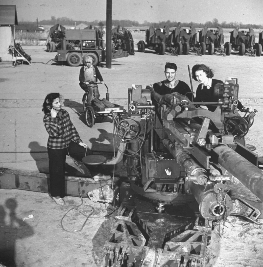 1942 年，一群男女在马里兰州阿伯丁试验场测试 90 毫米高射炮。二...