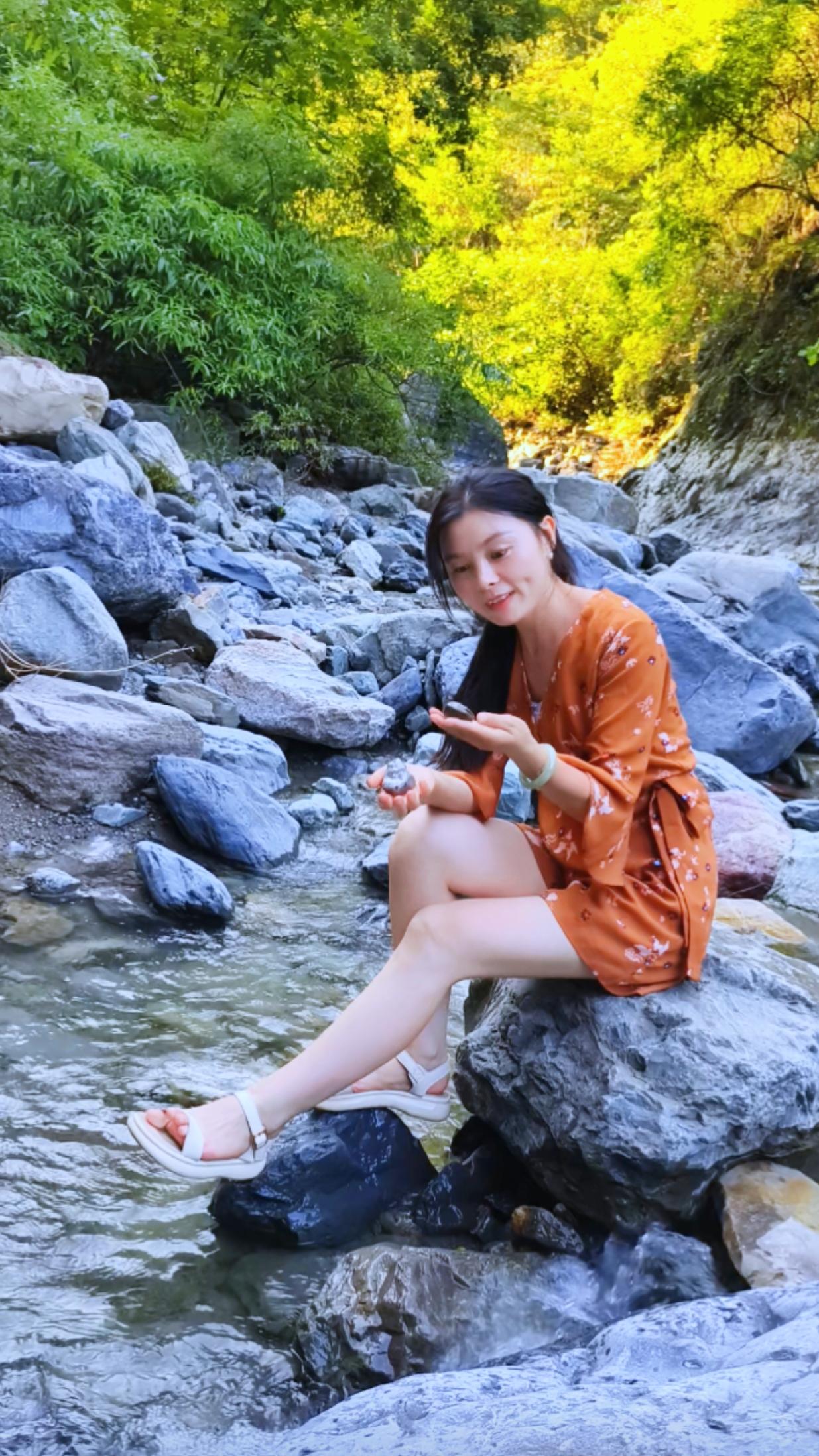 阳光明媚，女孩在溪边玩石头。