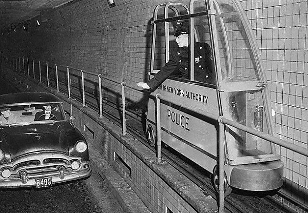 警察猫步车在纽约荷兰隧道运行，1954年。警察猫步车1300磅重，用电...