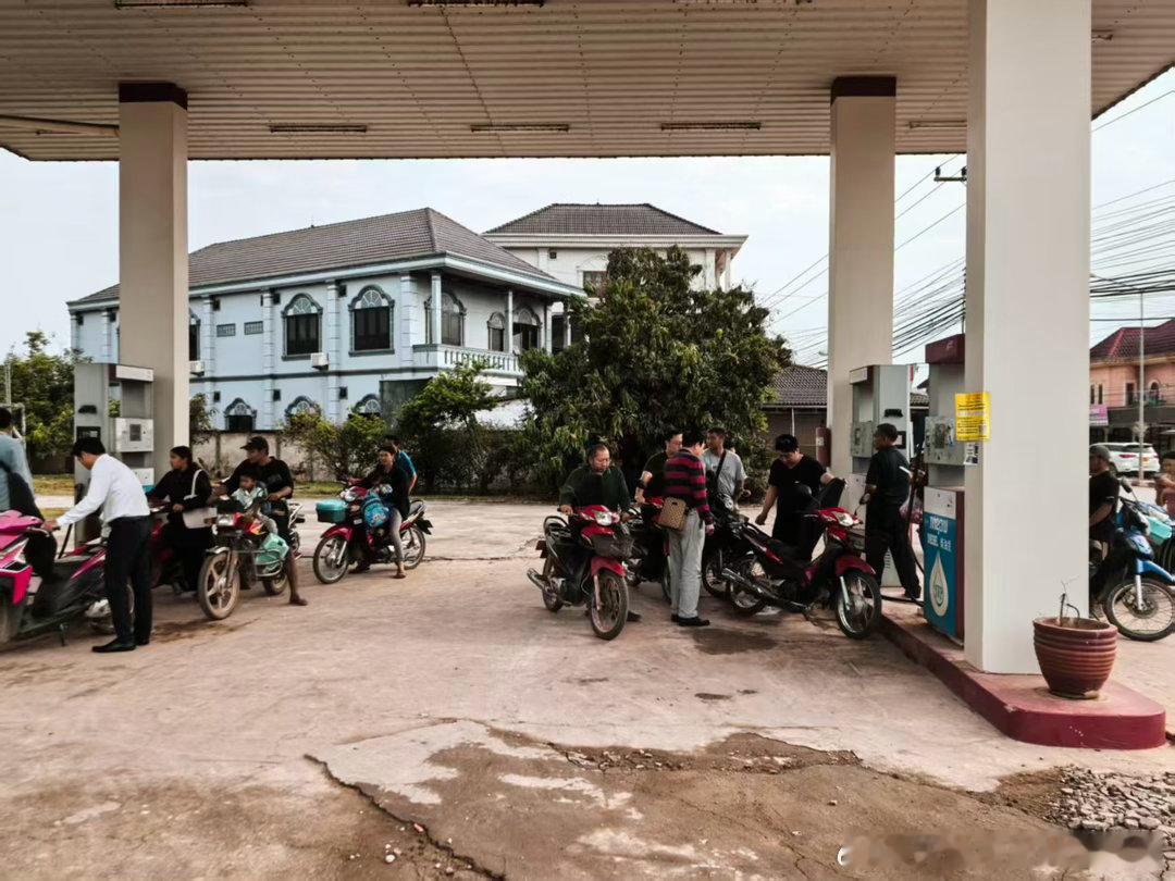 老挝加油站的人用饮料瓶装汽油。他们需要排队按瓶买汽油 