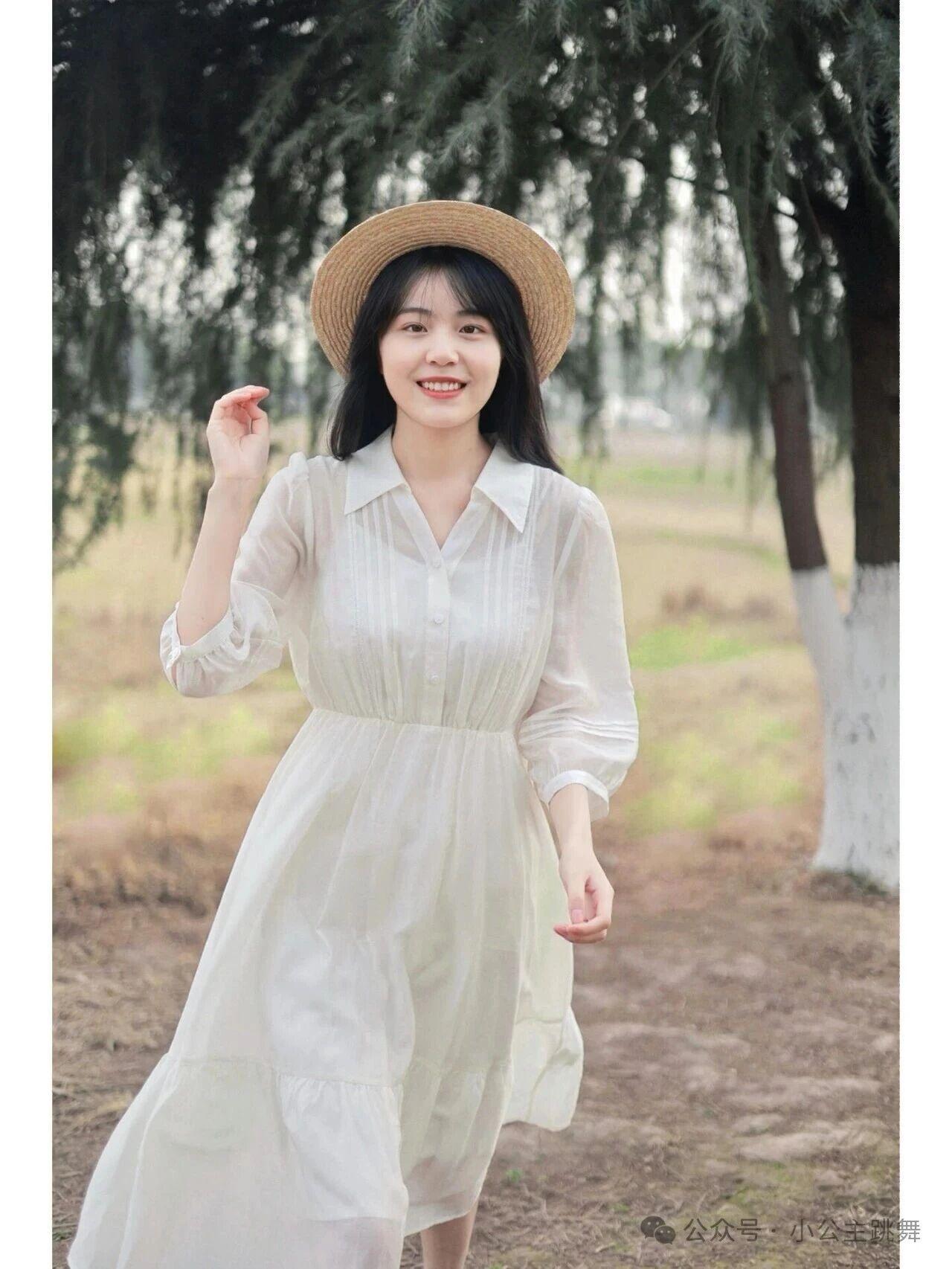 她身着一袭飘逸的白色雪纺长裙，轻盈的面料随风轻扬，简约的翻领与收腰设计勾勒出曼妙