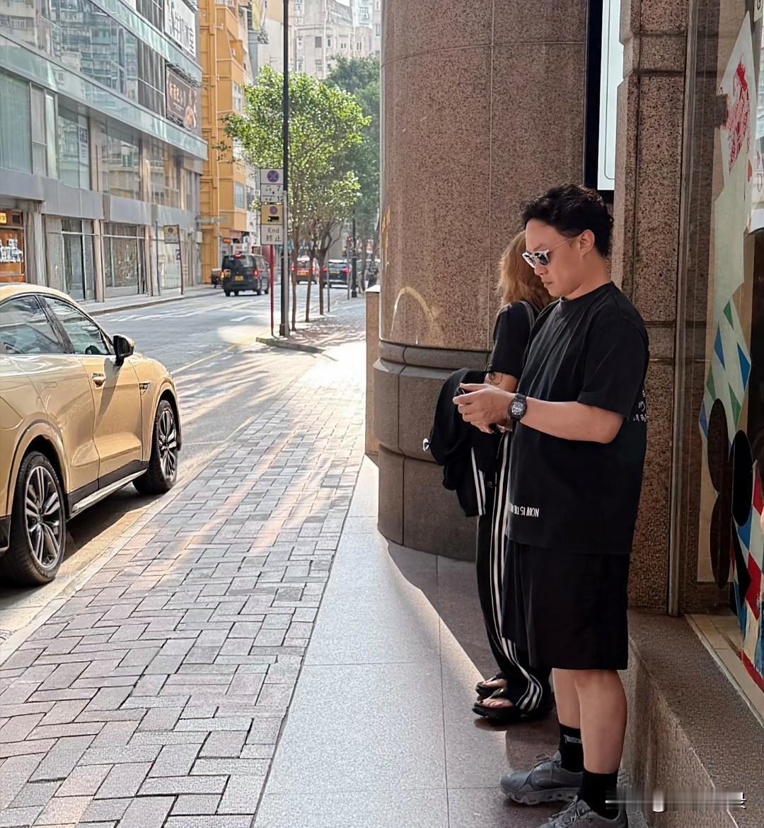 陈奕迅和老婆徐濠萦在香港街头等车，他现实中外形很普通，个子很矮，身材微胖，远不如