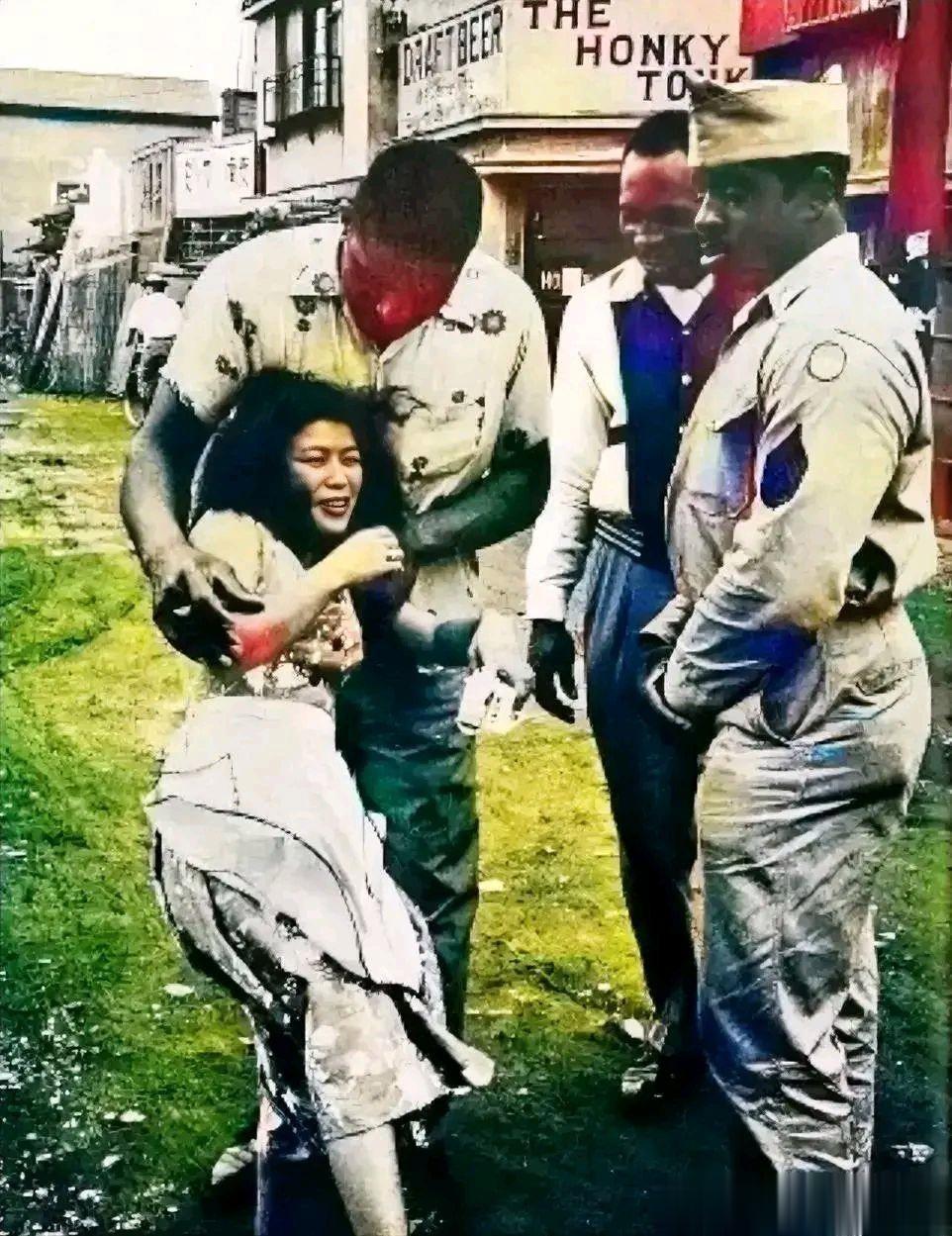 50年代，在日本街头，一个日本女人被三个不怀好意的黑人美国士兵强行搂抱调戏。
当