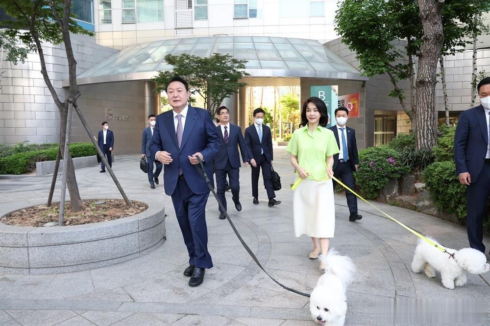当官就是威风，清晨两口子去遛狗，身后就跟着七八个随从，拎包是秘书，离得最近，走的