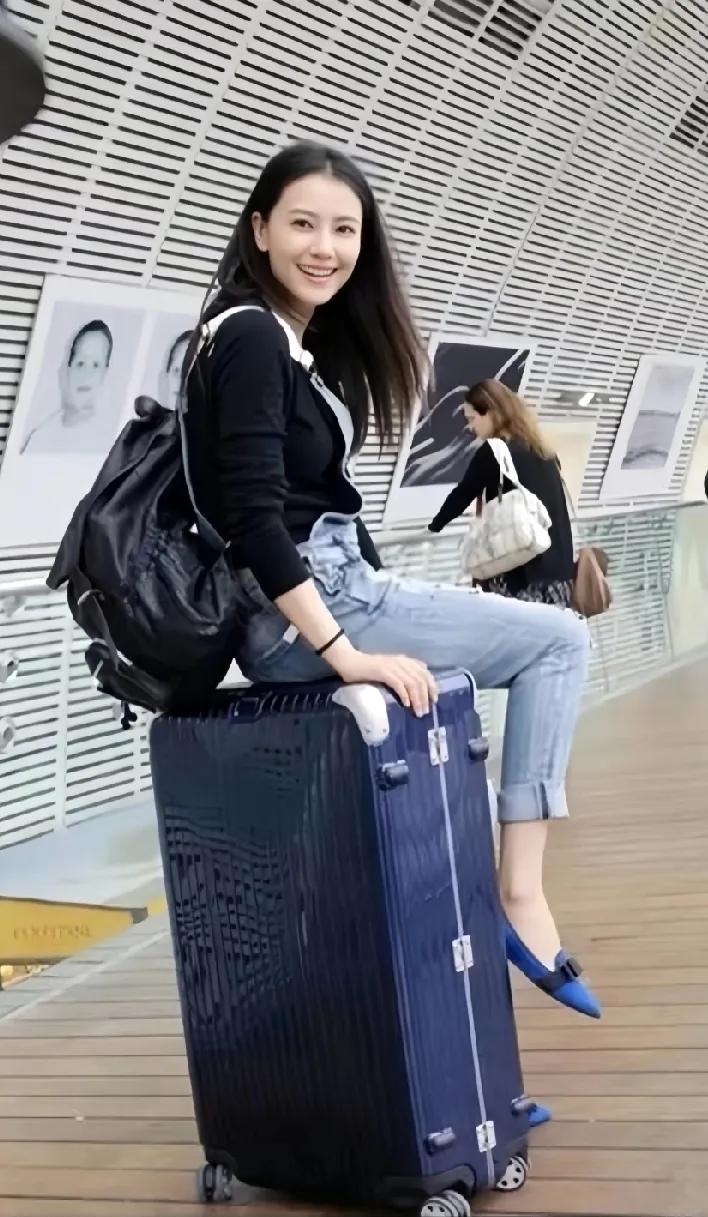 翻到高圆圆早年旧照，齐肩发配黑色双肩包，坐在行李箱上回眸笑，清新感扑面而来，年轻