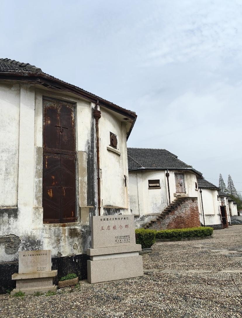 长水塘的波纹漫过石码头，十四座苏式圆筒仓静立成时光的锚点。青瓦六面体顶漏下细碎光