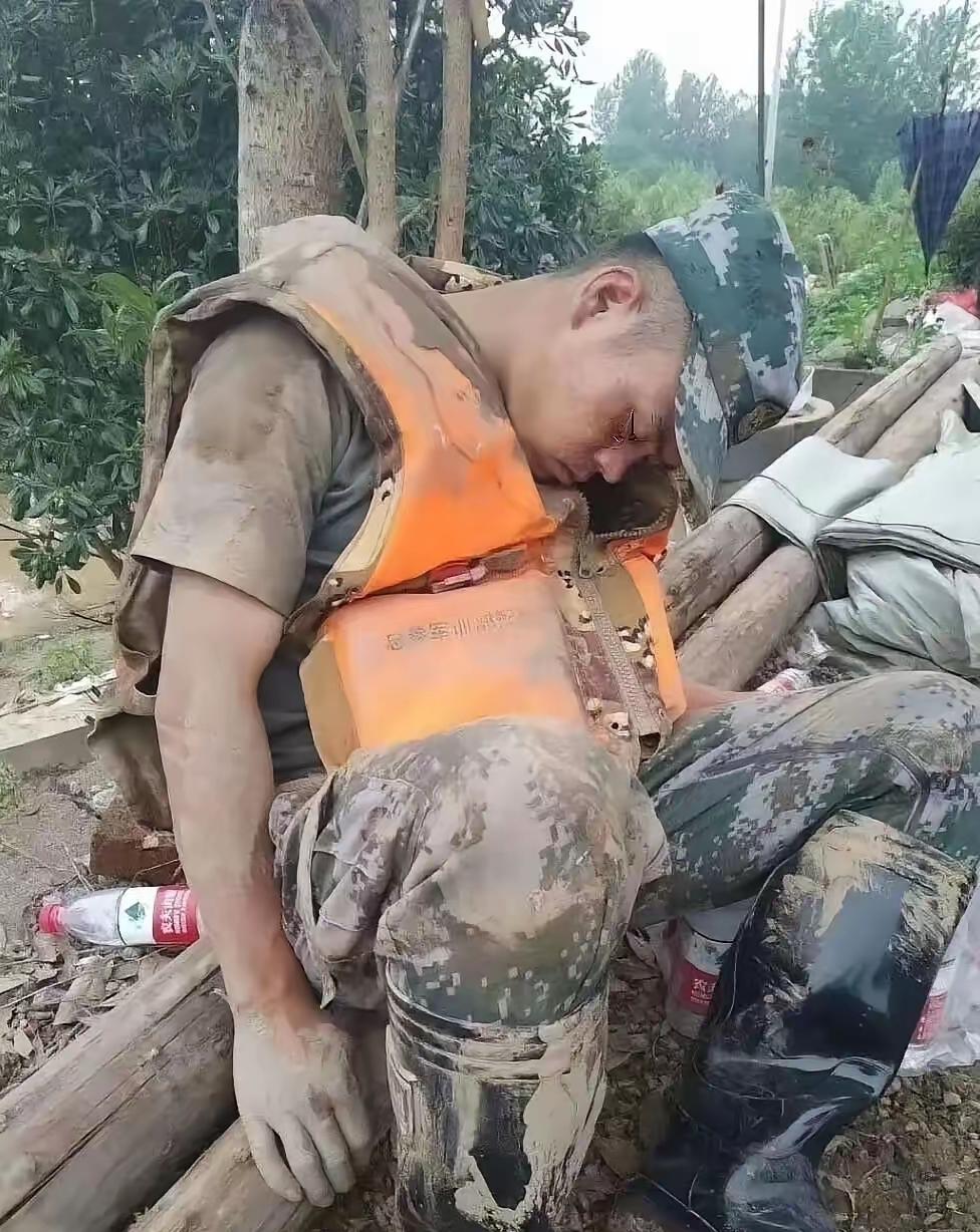 这张照片让无数人泪崩，一个满身淤泥的小伙子，累得靠在一棵树旁睡着了。

每每看到