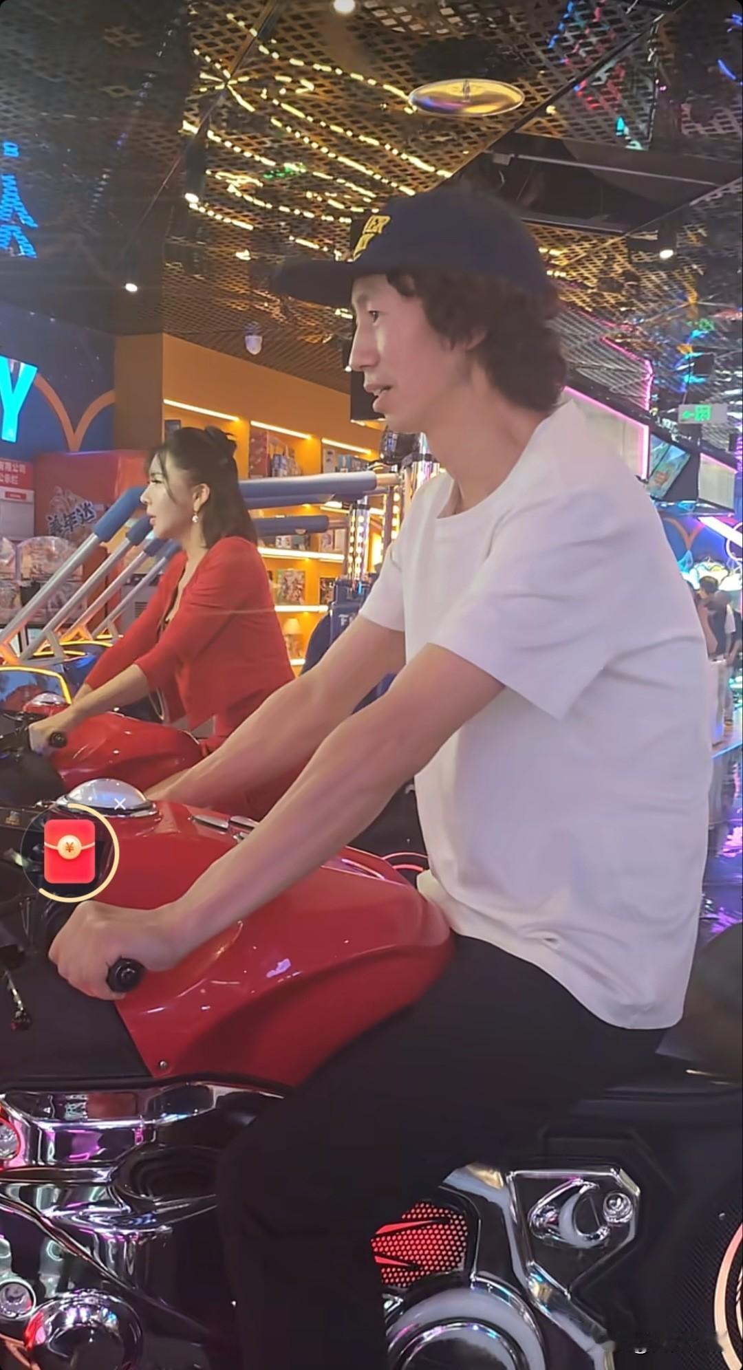 这俩人玩得可真开心！在电玩城里骑着摩托车，笑得那叫一个甜。更逗的是，俩人还一起开