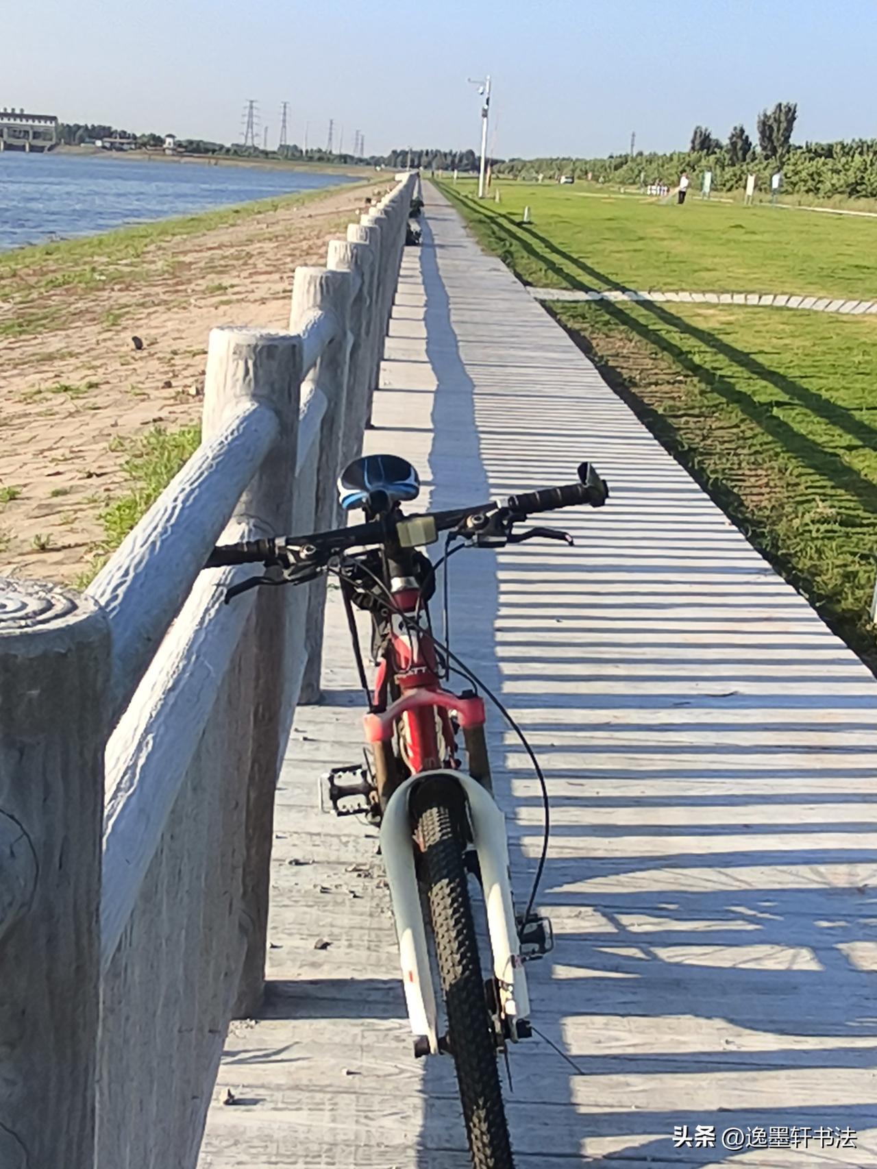 晒图笔记大赛晴日铺落长长的栏杆阴影，单车静立河畔步道，河水平缓流淌，青草漫延向远