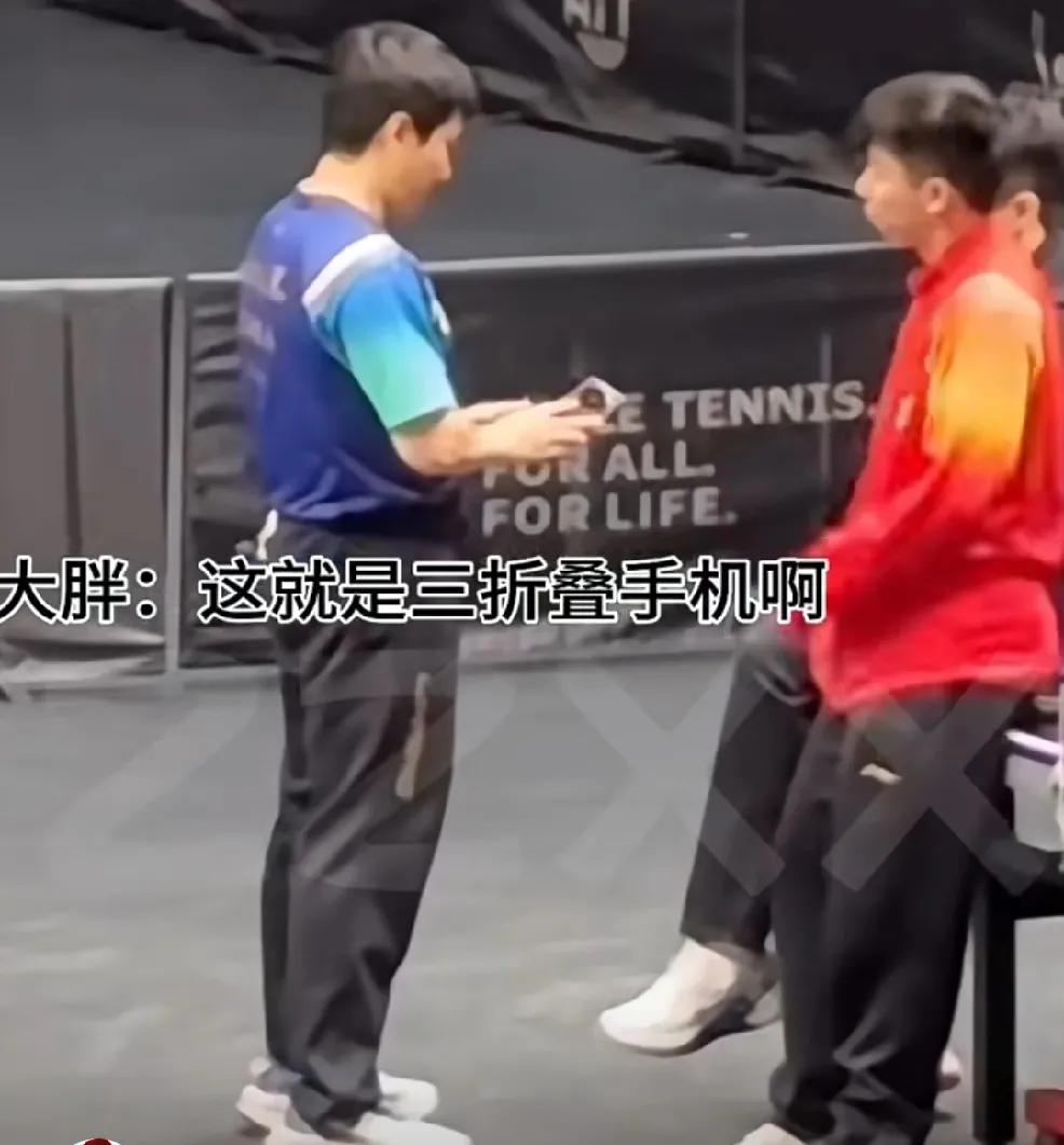 训练之余这几个人一起来研究头哥的三折叠，
甜甜拿在手里：这就是你的三折叠啊？哈哈