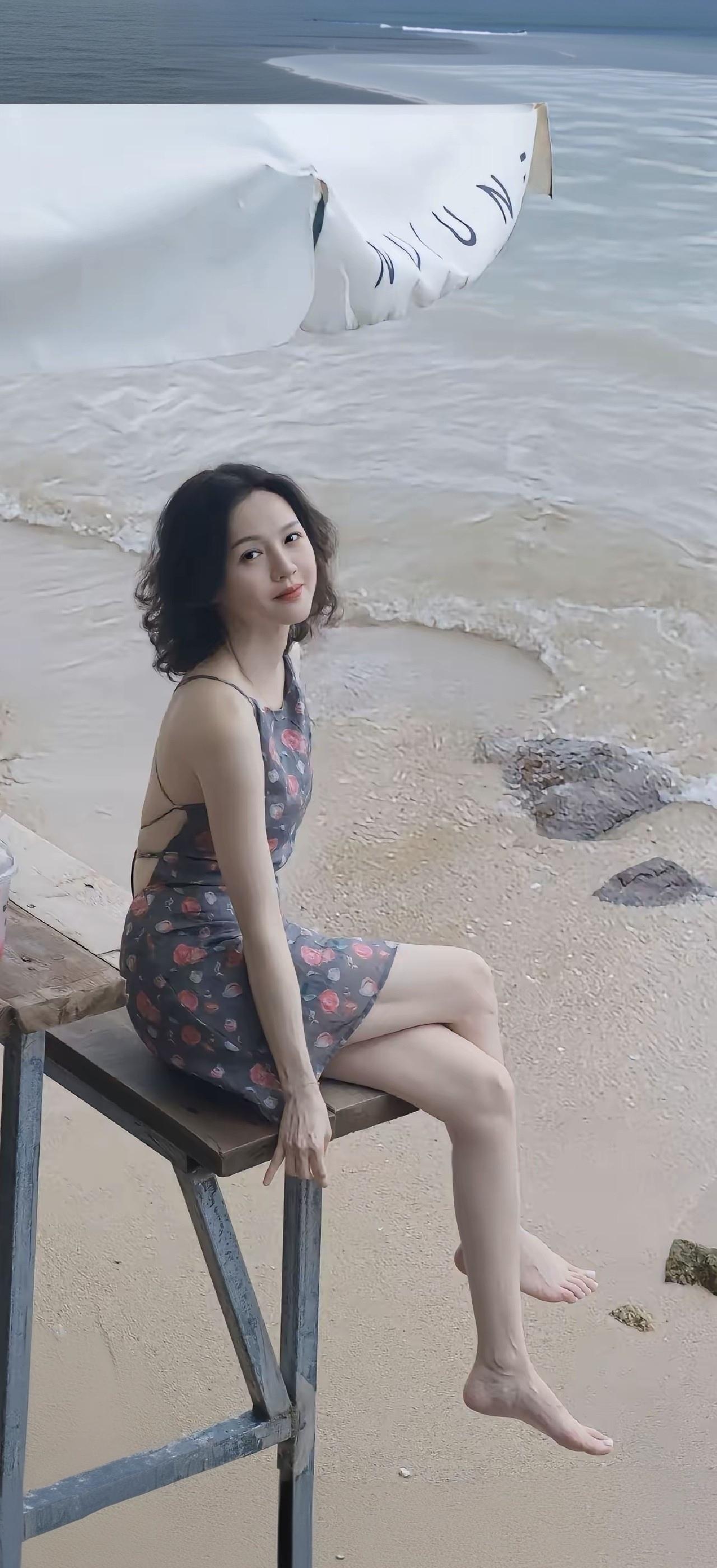 一个女孩坐在海滩边，海浪轻轻拍打着岸边。