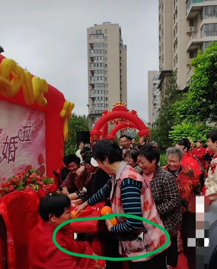 某小区这对新人正在举办结婚仪式，社区里面的大妈们已经忙不迭的开始抢桌子上的糖啊、