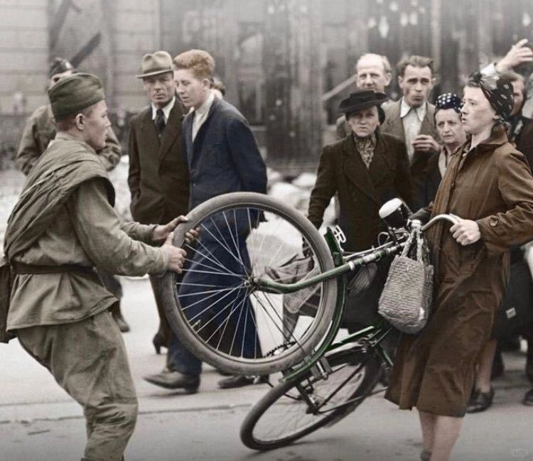 1945年，苏联红军士兵试图从一名德国妇女那里抢一辆自行车。打进德国后，苏联红军...