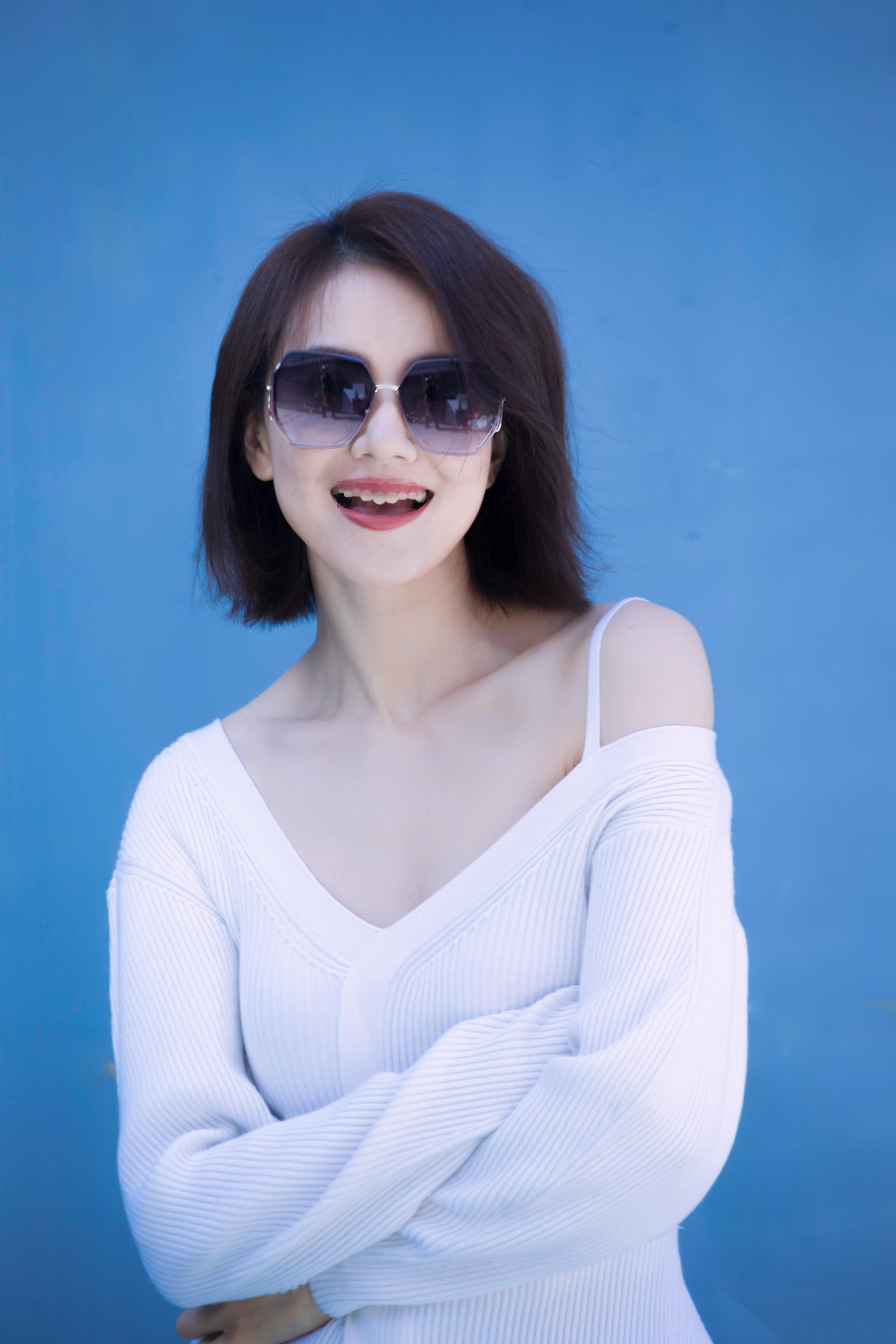 写真在色彩与氛围的把控上十分出色。纯净的蓝色背景与白色针织衫形成清爽对比，渐变粉
