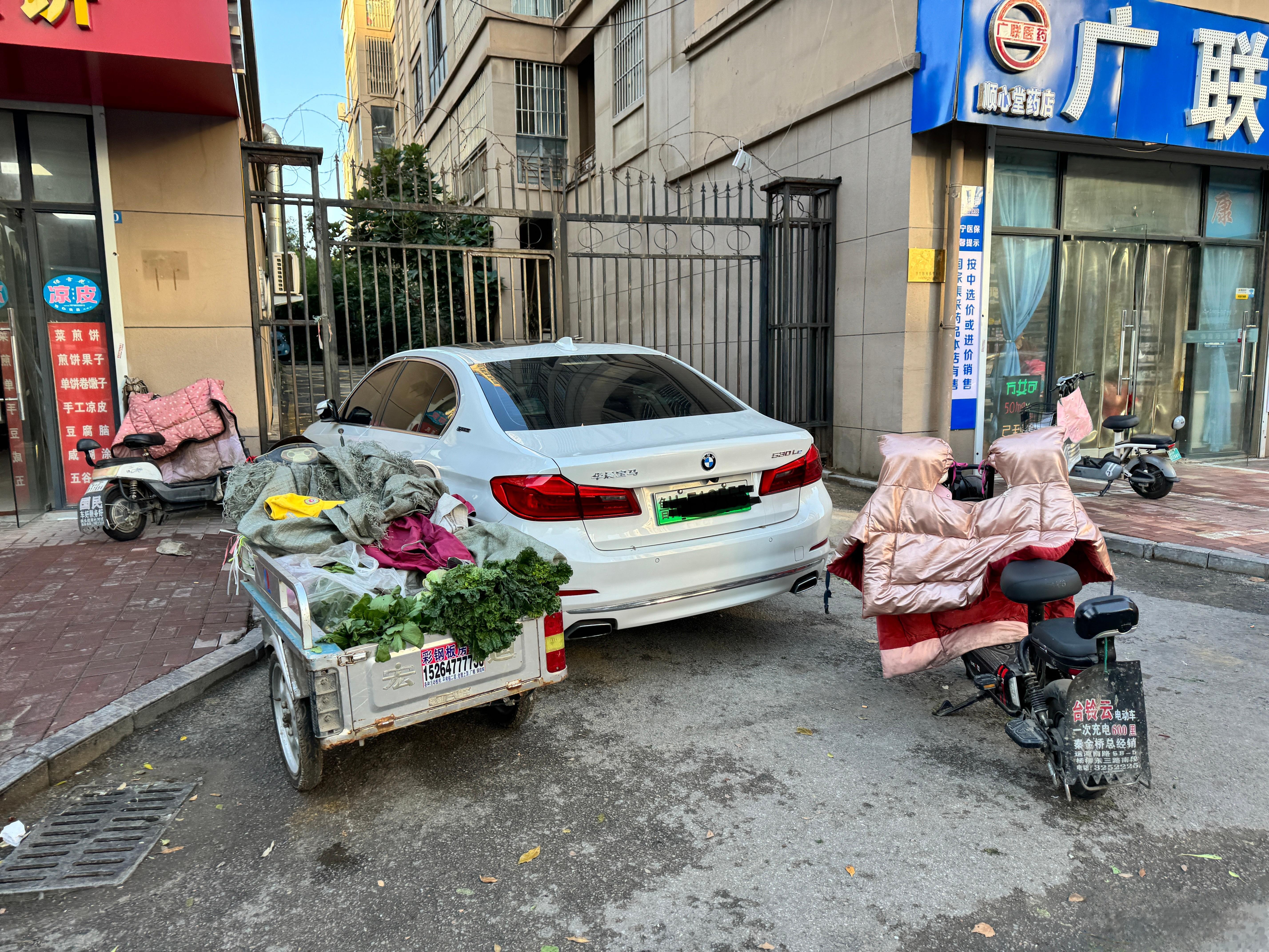 小区的消防通道上，被三轮车和电动车包围的豪车。宝马说，你们走开，别碰我，不然赔不
