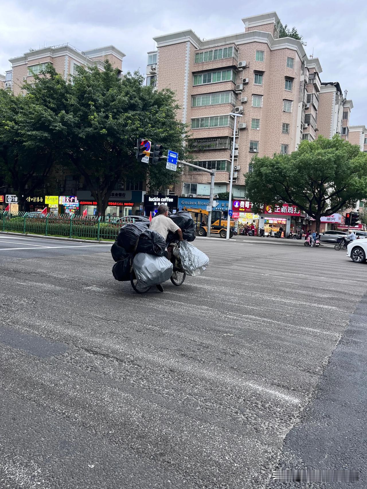 感觉他骑得特别累，因为前面还堆着垃圾袋高高的，连路面都看太清楚了。
他这么辛苦一