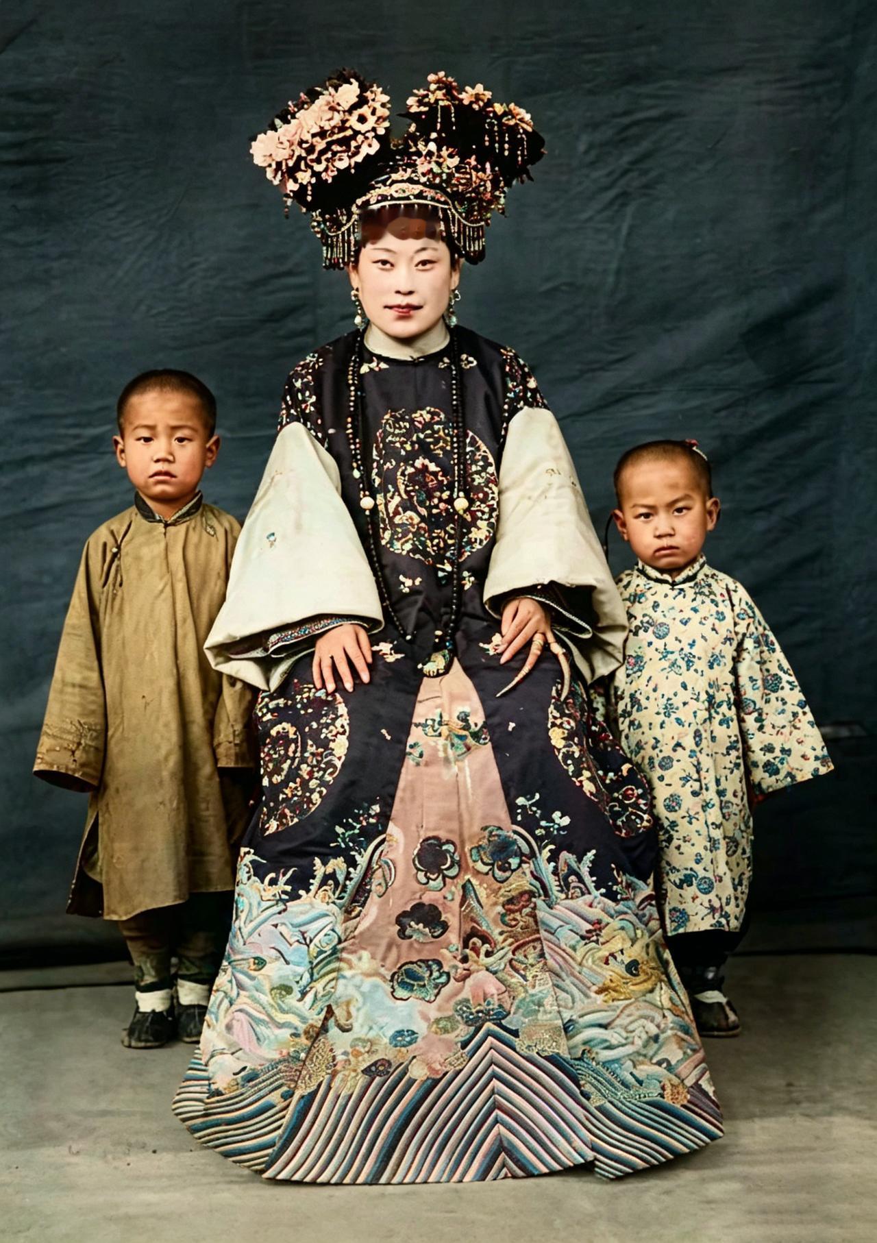 这张晚清老照片，定格了一位满族贵族女子与孩童的合影。

她身着绣满龙凤纹样的旗装