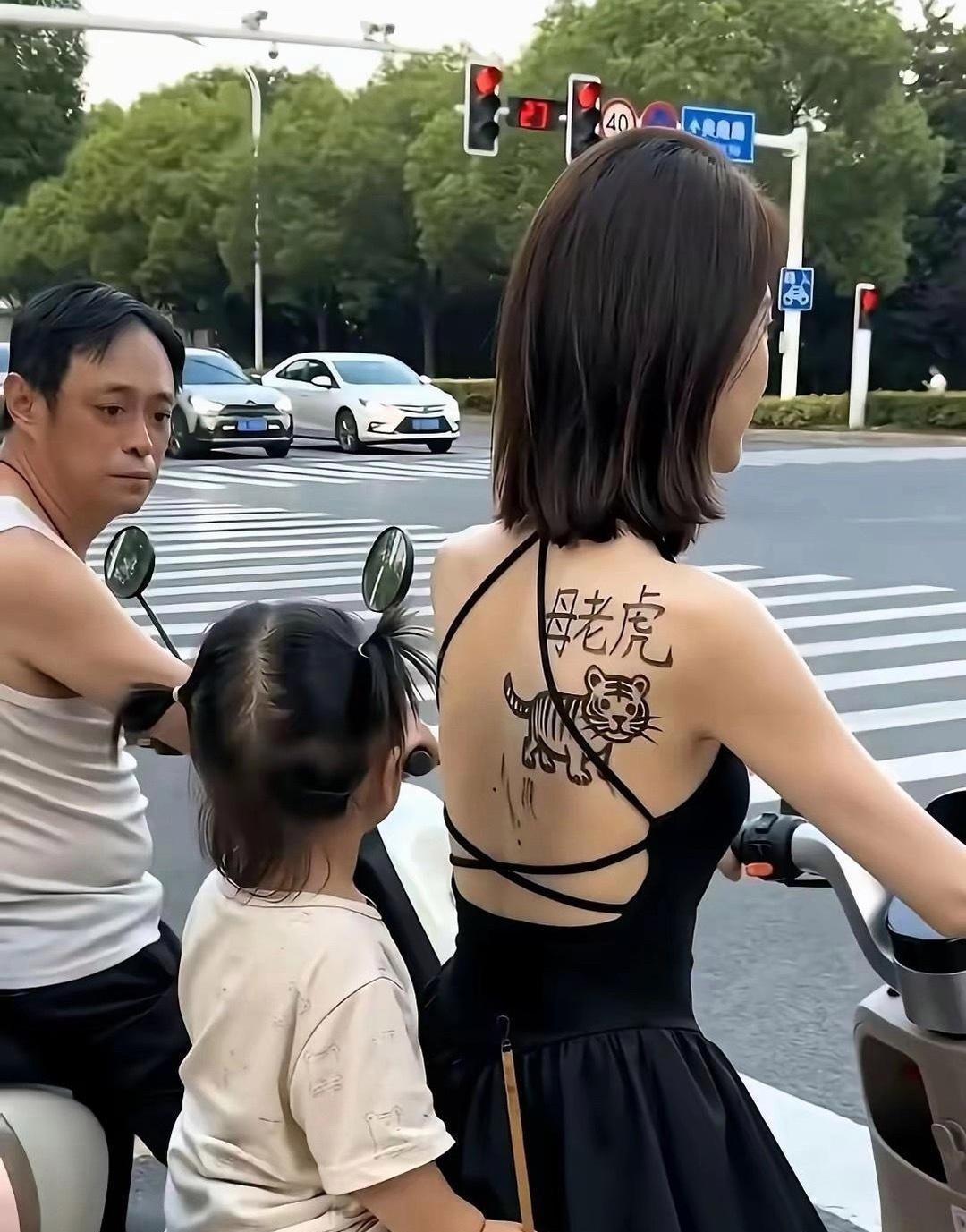 全网最美妈妈火了！骑着小电驴带着孩子，后背“母老虎”趣味纹身瞬间出圈。外表霸气，