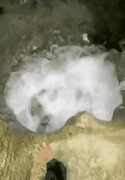 几名男子在山上的小溪里游泳，一名男子发现一块巨大的石头下面一条缝隙和一处水洞相连