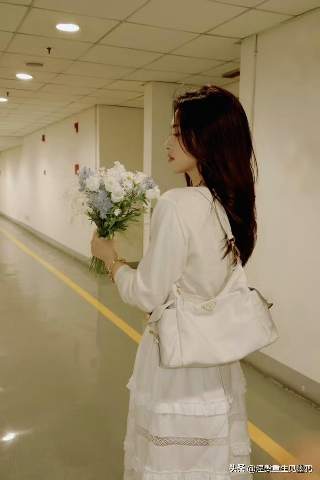 朱珠回眸
朱珠着一身米白裙装，长发垂落肩头，怀抱着一束清浅花束。她一回眸，发梢顺