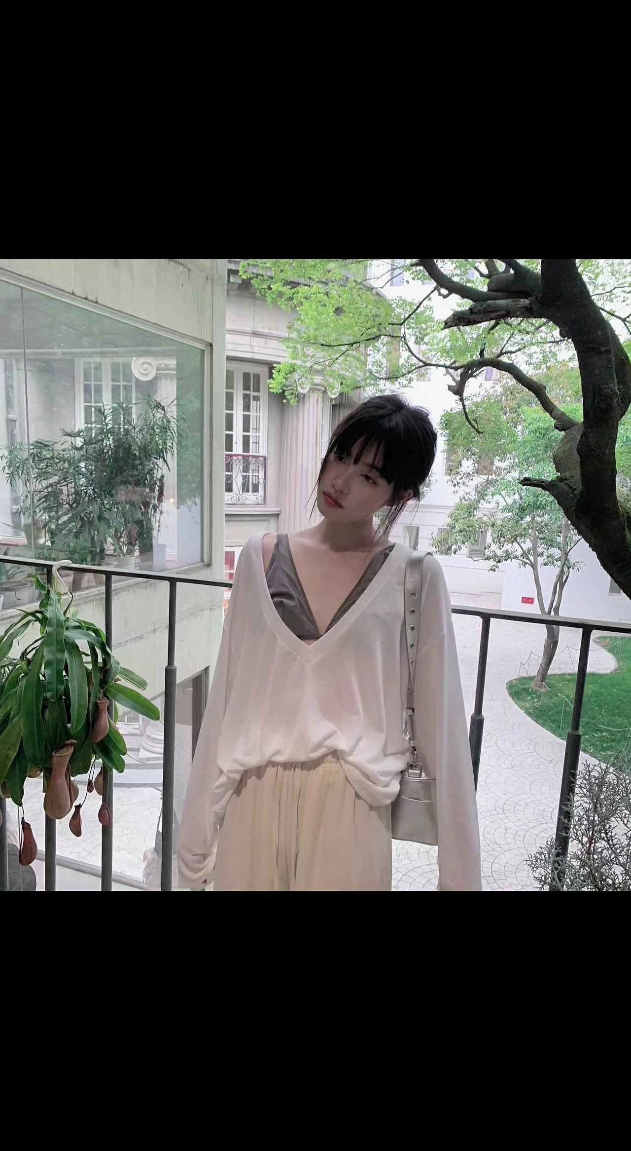 🌿光影在V领游走，像春天在领口写诗✨。旧栏杆爬满时光，树影摇晃成流动的绿纱☘️