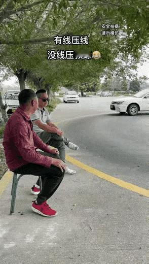 教练幸亏反应快！
一个教练坐在一边的凳子上陪着一朋友聊天。这时，车里的司机徒弟，