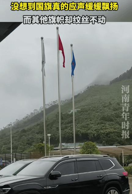 广东一名男子雨天路过广场，看到三根旗杆上的三面旗帜全被雨水浸透，他对着中间的五星