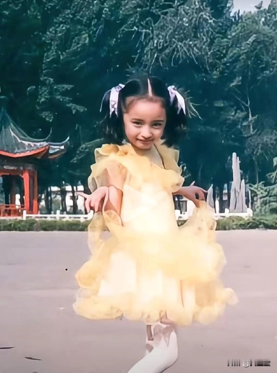 二十多年前的公园广场，这个穿着蓬松黄裙子的小女孩，扎着俏皮的蝴蝶结，正踮着脚尖快
