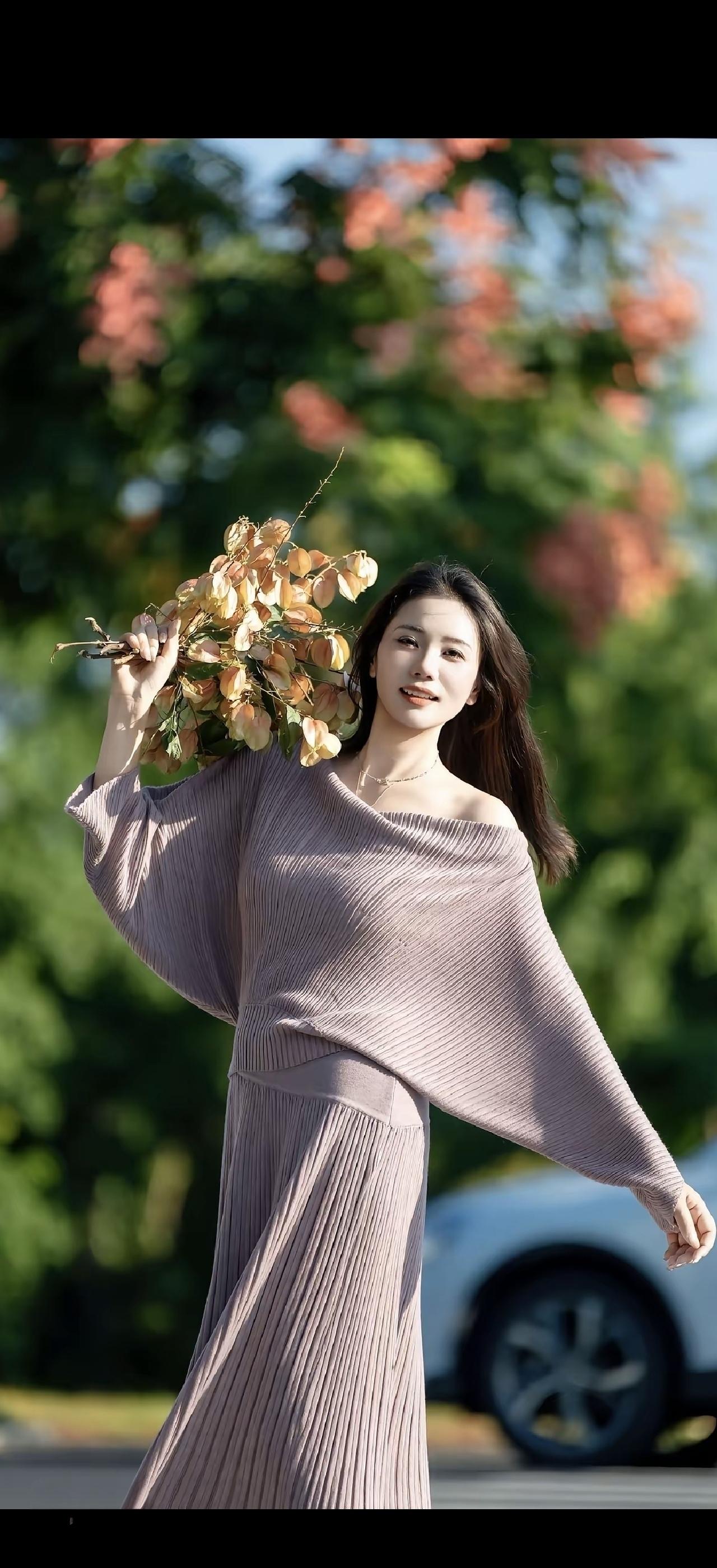 女孩拿着花在阳光下微笑。