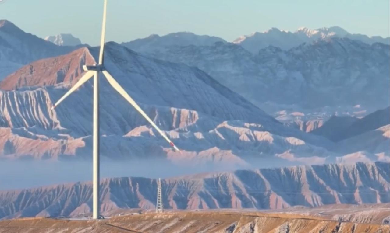 在连绵起伏的山峦与广袤无垠的旷野之上，一座座白色的风力发电机矗立其间，巨大的叶片