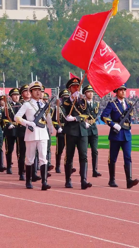 向右看，一二。现在迎面向我们走来的是阶梯工业大学国旗护卫队。