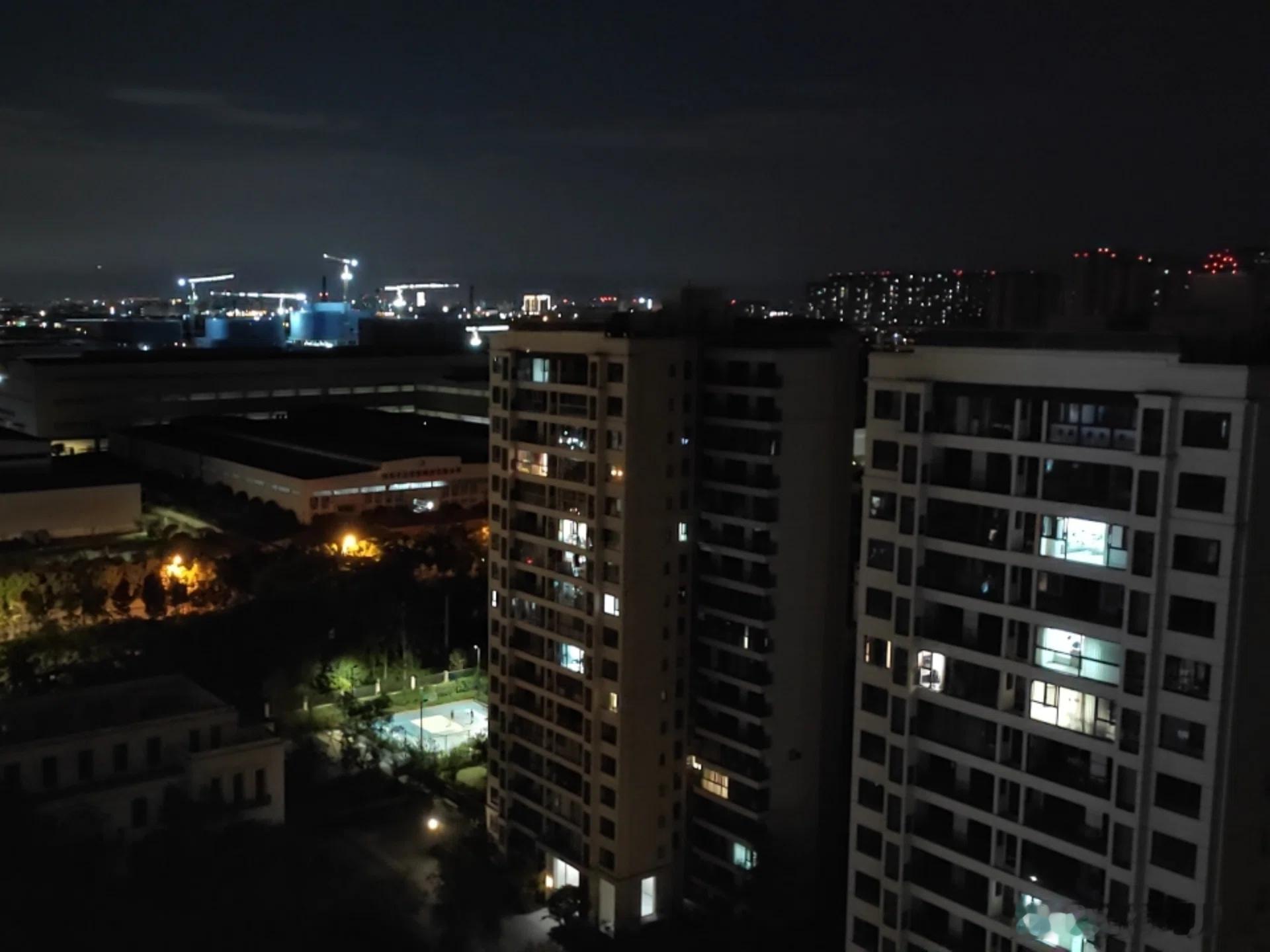 白日喧嚣归于沉寂，夜色漫过楼栋缝隙。有的窗户亮着居家的暖意，远方工地塔吊亮着奋斗