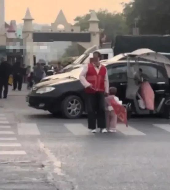 宝妈带娃站马路，一手举旗一手拽衣领。最近深圳这幕让人揪心！

视频里，孩子被扯着